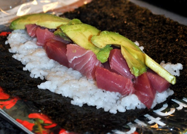 Making a tuna sushi roll.