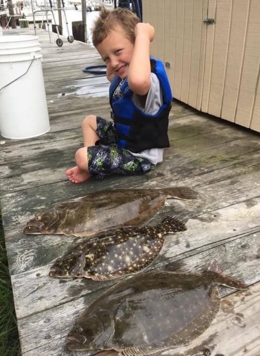 Four-year-old Austin Doidge flexes his muscles next to the 24-inch doormat he caught on Barnegat Bay with his grandfather this week. 