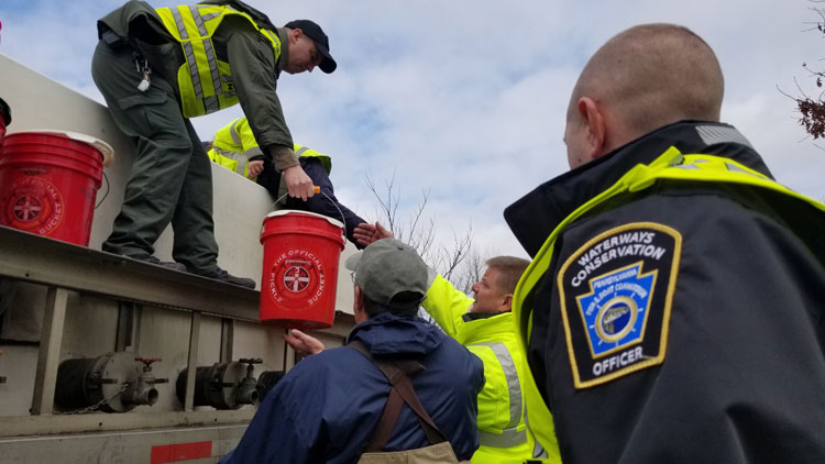 Sgt. Rhoades handing a bucket of trout