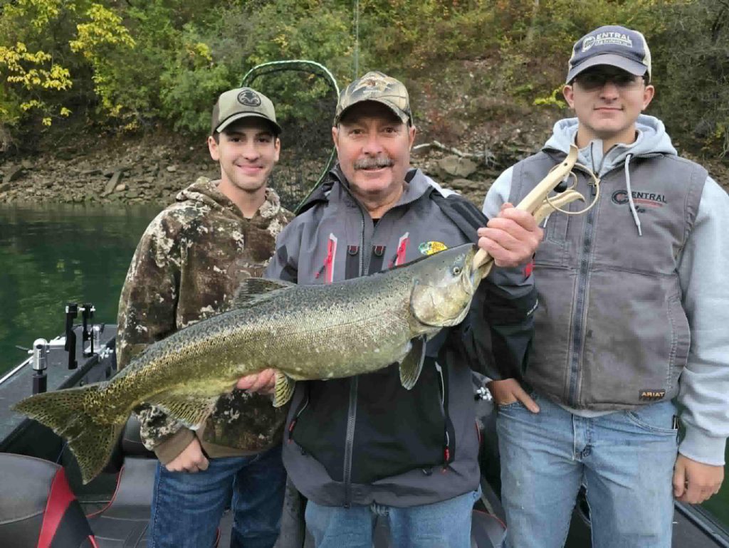 Frank Mazza of New Jersey holds up a salmon in Devil's Hole with his sons Lee and Oliver.