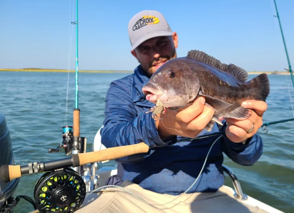 an angler poses with a tautog caught on the fly in the summertime